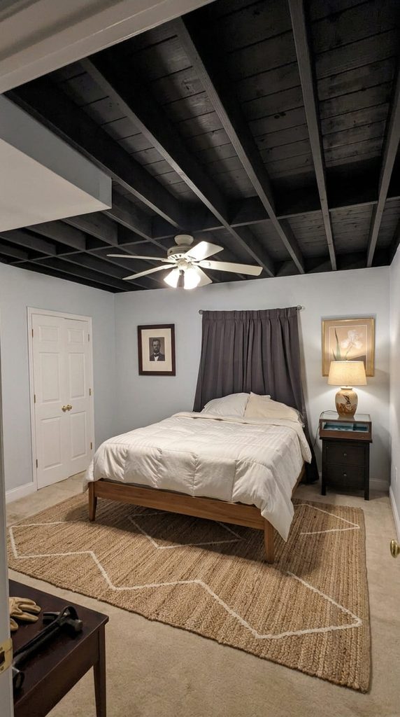 Basement bedroom ceiling with exposed rafters painted black